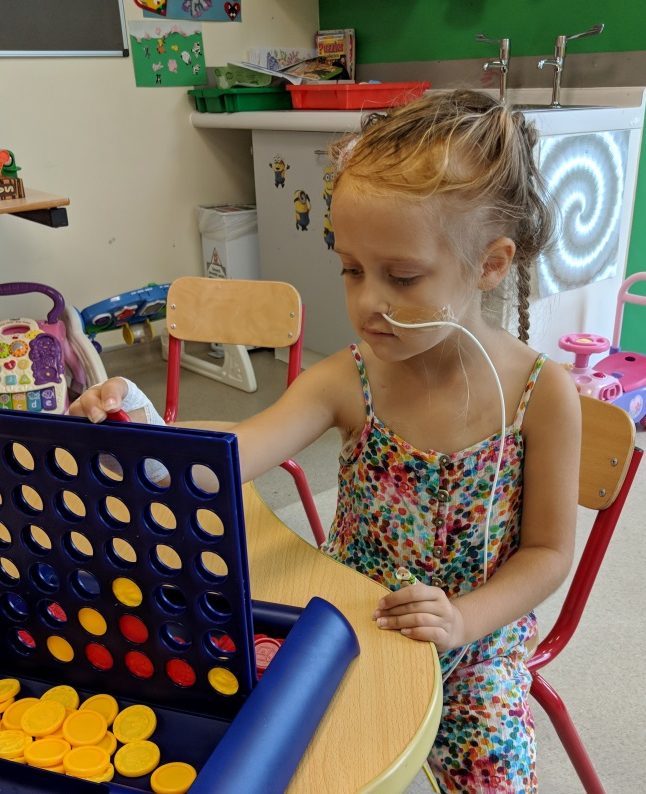 Patient with brain tumour at Royal Manchester Children's Hospital charity playing Connect 4